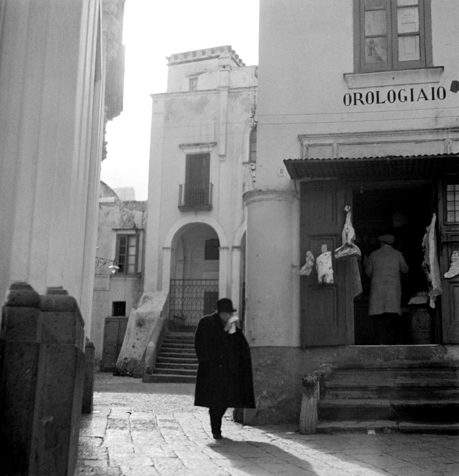 Man op een pleintje in Anacapri, rechts een horlogemaker, Bestanddeelnr 252-0062