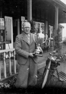 Man outside Llandrindod Wells Golf Club pavilion holding a cup (1293384)