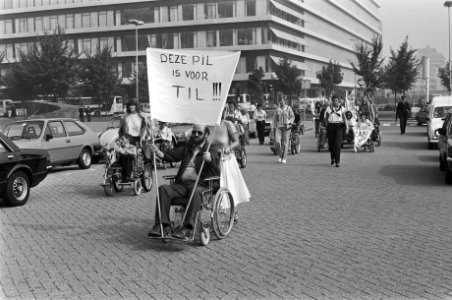 Man in rolstoel met spandoek Deze pil is voor Til, Bestanddeelnr 932-3265