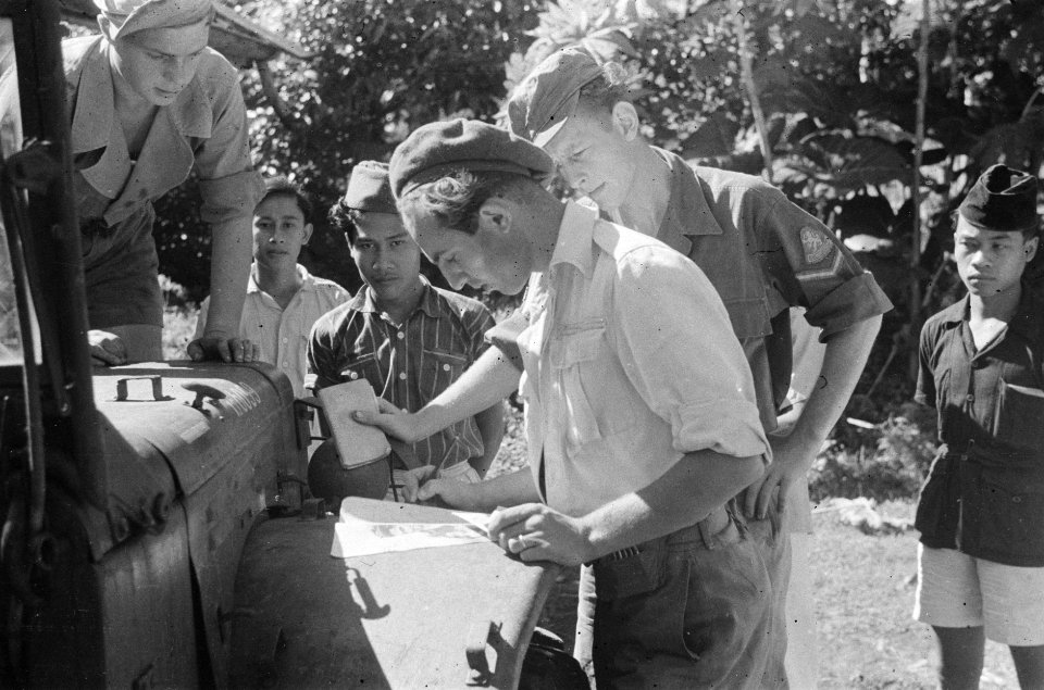Man in uniform en baret bekijkt een kaart op het spatbord van een driekwarttonne, Bestanddeelnr 455-1-5