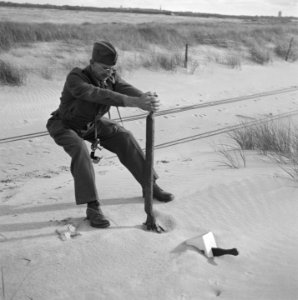 Man in uniform (met fotocamera om de hals) probeert aan de handel van een spoorw, Bestanddeelnr 900-6208