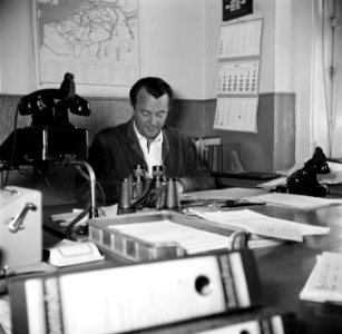 Man achter bureau met ordners, vermoedelijk dhr. Stevens aan zijn bureau in het…, Bestanddeelnr 254-0977