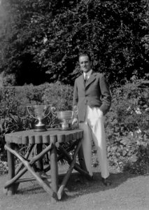 Man standing next to a garden table on which are two golfing trophies (1294351)