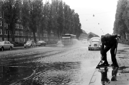 Man met schep bij een afvoerput in de ondergelopen Rooseveltlaan, Bestanddeelnr 927-9931