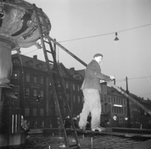 Man staat op een plank op de Caritas fontein aan het Gammeltorv, Bestanddeelnr 252-8684