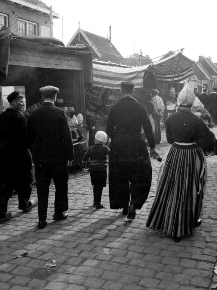 Mannen, vrouw en kind lopend over de kermis in Volendam in klederdracht, Bestanddeelnr 190-1076