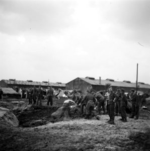 Mannen aan het graven, op de achtergrond barakken, Bestanddeelnr 900-3392