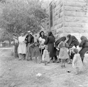 Mannelijke verpleegkundige met arabische mannen, gesluierde vrouwen en kinderen , Bestanddeelnr 255-0947