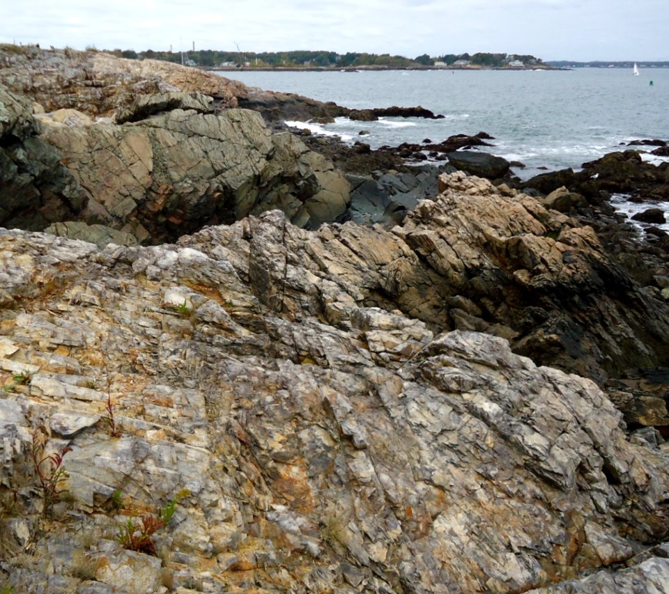 Marblehead Massachusetts view from peninsula of rocks and harbor entrance with sailboat