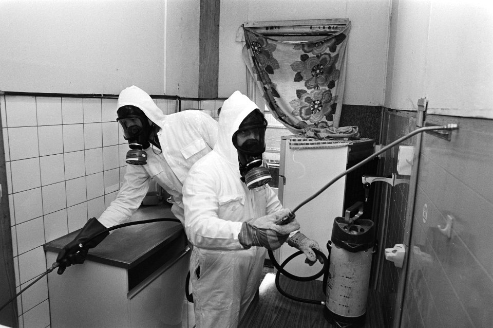 Mannen in beschermende kleding bespuiten een keuken ter bestrijding van kakkerla, Bestanddeelnr 931-2643