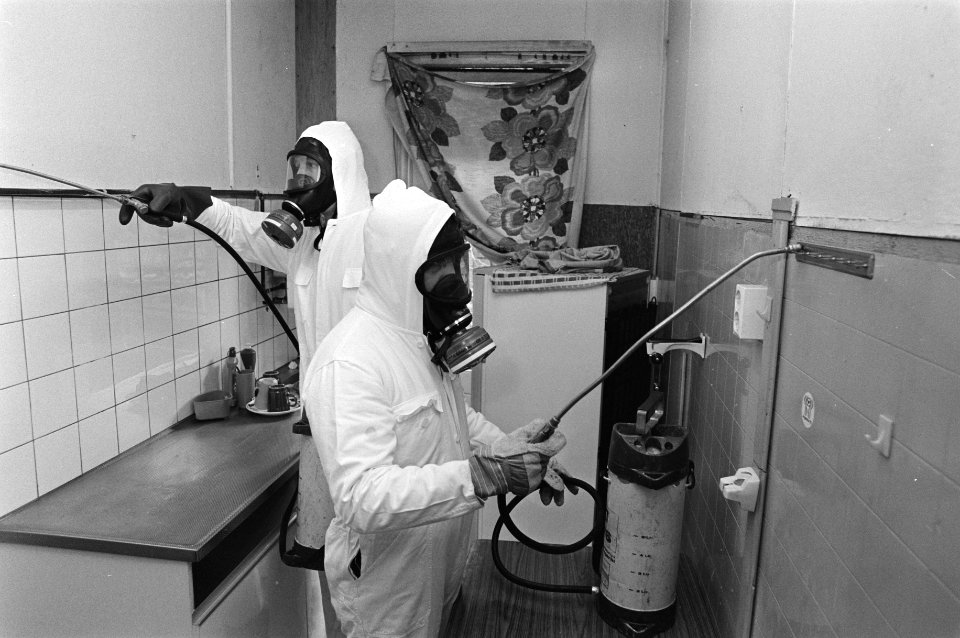 Mannen in beschermende kleding bespuiten een keuken ter bestrijding van kakkerla, Bestanddeelnr 931-2644