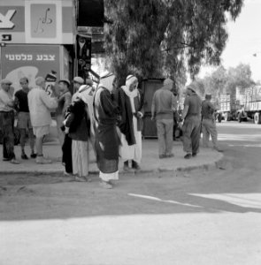 Mannen pratend op het trottoir, in het midden een groep bedoeïenen, Bestanddeelnr 255-3437
