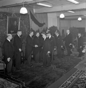 Mannen schudden handen tijdens receptie, links aan de wand een portret van Henri, Bestanddeelnr 255-8503