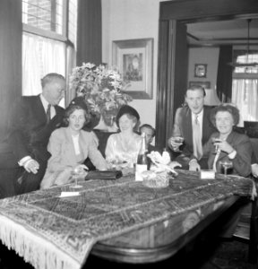 Mannen en vrouwen poserend achter een tafel met een drankje, Bestanddeelnr 255-8518