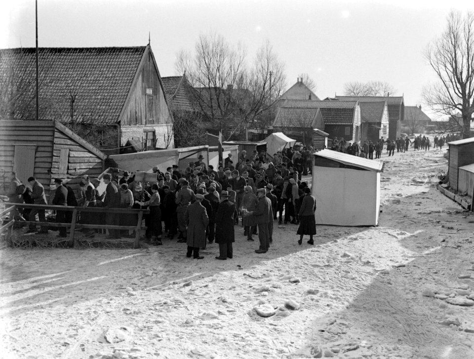 Mensen bij een sloot waarop geschaatst wordt en waar langs de kant koek-en-zopie, Bestanddeelnr 189-1067