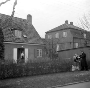Meneer Svendsen wordt bij het tuinhek begroet door zijn kinderen terwijl zijn vr, Bestanddeelnr 252-8759