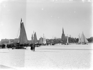 Mensen bij de ijszeilers en een auto op het ijs van de Gouwzee met op de achterg, Bestanddeelnr 189-1070