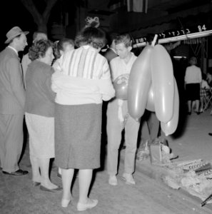 Mensen in groepjes op straat, ze bekijken feestartikelen, Bestanddeelnr 255-1927