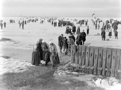 Mensen komen via houten planken en over stro met hun schaatsen van het ijs met o, Bestanddeelnr 189-1074