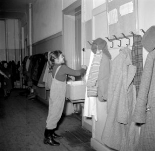 Meisje bij een wasbak in een gang met jassen aan kapstokken, Bestanddeelnr 252-8960