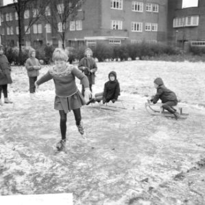 Meisje bij het schaatsen met op de achtergrond kinderen op sleetjes, Bestanddeelnr 918-4691