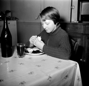 Meisje breekt een stukje brood af bij haar maaltijd, Bestanddeelnr 252-9390