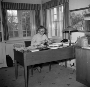Mevrouw Svendsen bestudeert een bot zittend aan een bureau waarop boeken en bott, Bestanddeelnr 252-8749