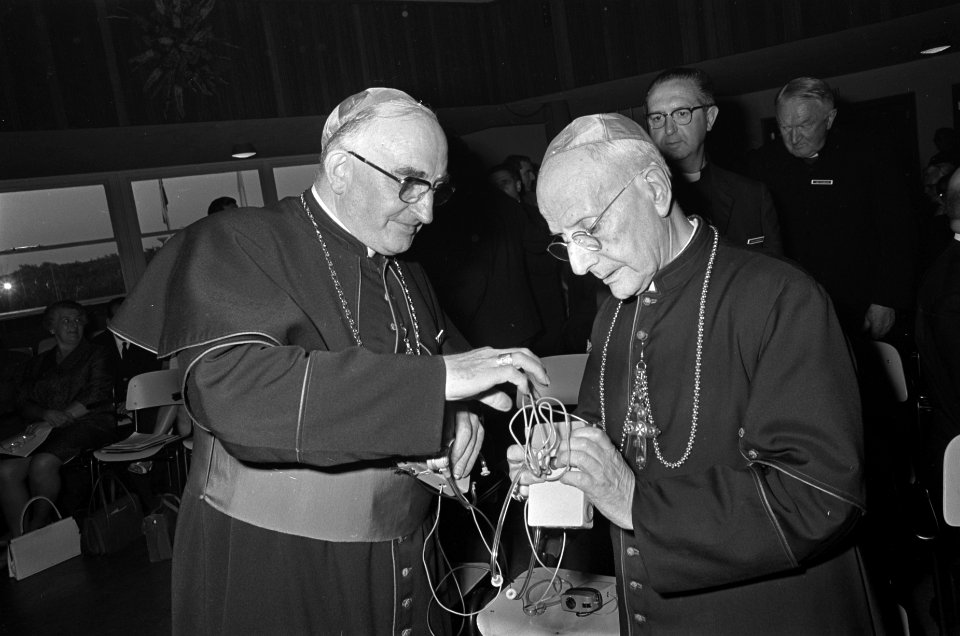 Mgr. M. Jansen (links) demonstreert een koptelefoon voor de bisschop van Malta m, Bestanddeelnr 920-4924