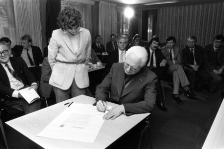 Mgr. Zwartkruis zet zijn handtekening, achter hem Frits Bolkestein (VVD), Van de, Bestanddeelnr 931-8385