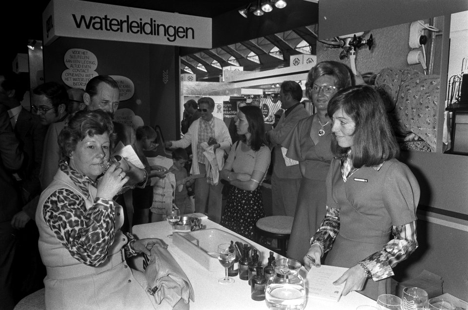 Mevrouw Kuypers keurt drinkwater op Huishoudbeurs, Bestanddeelnr 927-1344
