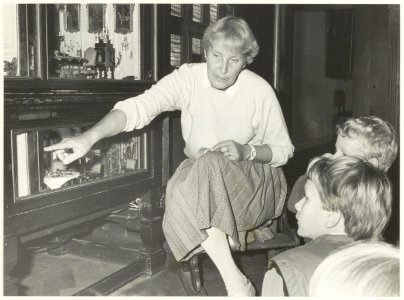 Mevrouw Boogaarts, medewerkster Frans Halsmuseum, geeft kinderen uitleg over het poppenhuis. NL-HlmNHA 54021217