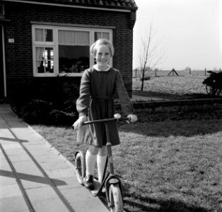 Marietje, de achtjarige dochter van Gerard, op haar autoped in de voortuin, Bestanddeelnr 254-3302
