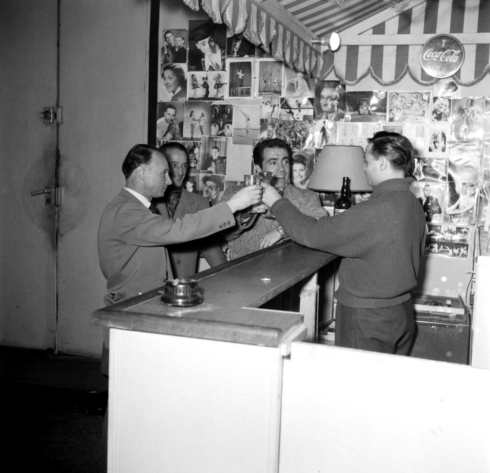 Meester Carletti achter de bar van de school. Aan de muren hangen fotos van ber, Bestanddeelnr 254-0132