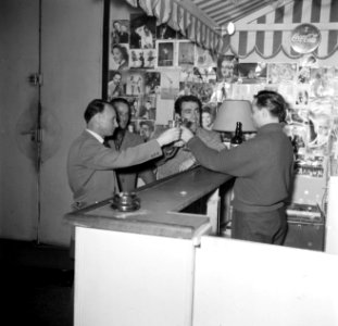Meester Carletti achter de bar van de school. Aan de muren hangen fotos van ber, Bestanddeelnr 254-0132