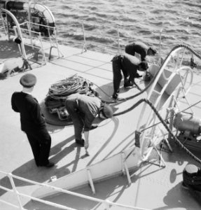 Matrozen bezig met werkzaamheden op dek van en schip terwijl officier toekijkt, Bestanddeelnr 934-5138