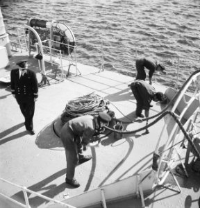 Matrozen bezig met werkzaamheden op dek van en schip terijl officier toekijkt, Bestanddeelnr 934-5136