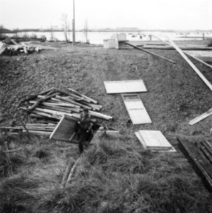 Materialen voor barakkenbouw liggen verspreid tegen de dijk, Bestanddeelnr 900-7600