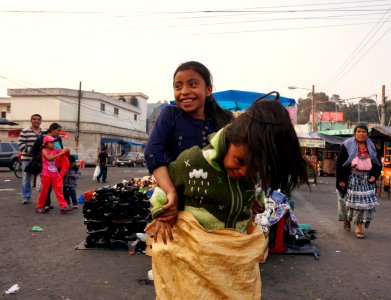 Mayan girls playing sack race on the market of Quetzaltenango, Guatemala