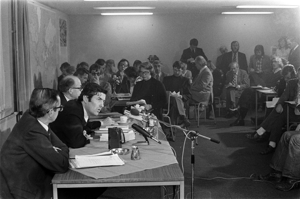 Moment uit de persconferentie minister aan het woord, op de achtergrond journal, Bestanddeelnr 926-7932