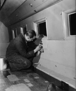 Monteur bezig met het interieur van een vliegtuig, Bestanddeelnr 901-4171