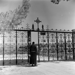 Monnik, vermoedelijk een franciscaan, in habijt bij het hek voor de kerk van de , Bestanddeelnr 255-0441 photo