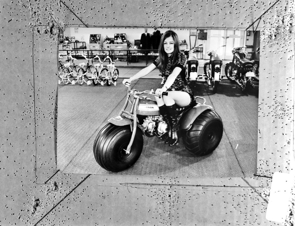 Model op driewielige motor, op de achtergrond kinderfietsjes en bromfietsen, Bestanddeelnr 924-3420