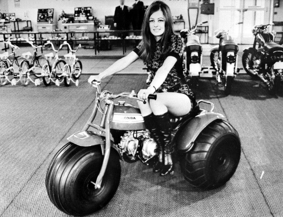 Model op driewielige motor, op de achtergrond kinderfietsjes en bromfietsen, Bestanddeelnr 924-3420 (cropped)