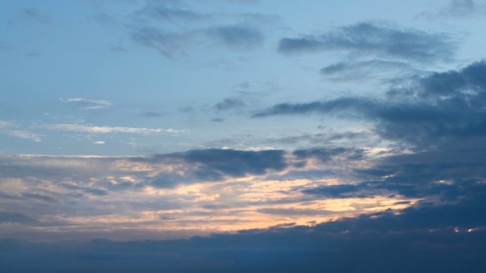 Mixed clouds covering setting sun