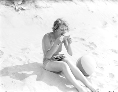 Model Eva Waldschmidt zit in het zand en stift haar lippen, Bestanddeelnr 252-0776