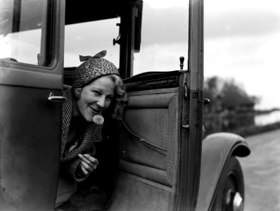 Model Eva Waldschmidt in een auto blaast pluisjes van een paardenbloem, Bestanddeelnr 189-0438