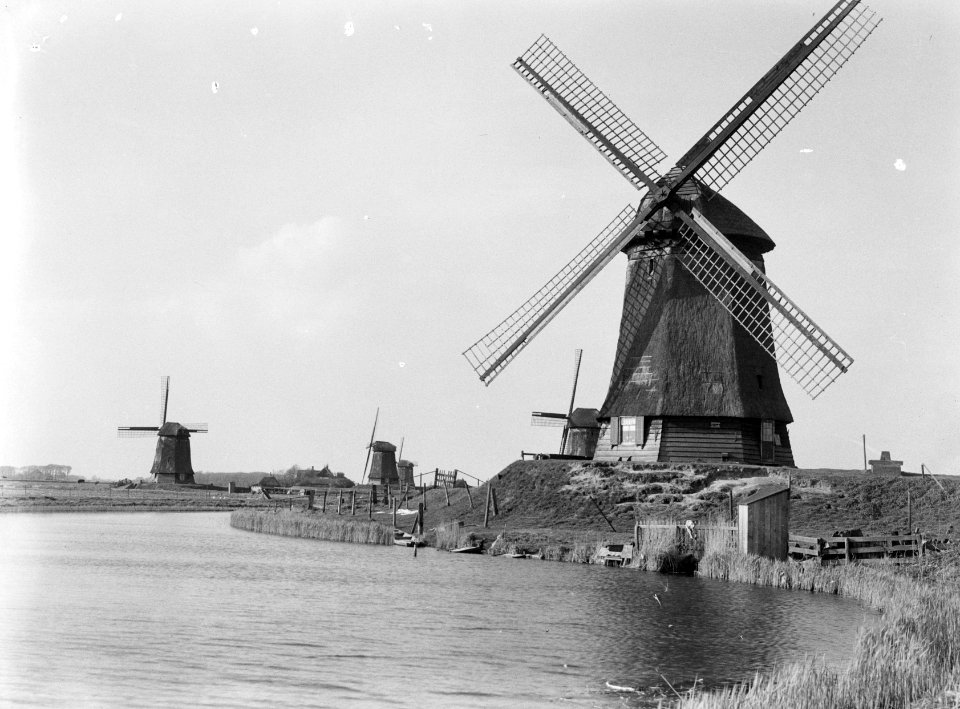 Molen op voorgrond in polderlandschap met vier kleine links in achtergrond, Bestanddeelnr 190-0250