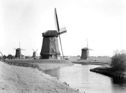 Molen op voorgrond in polderlandschap met twee kleine links en een rechts, Bestanddeelnr 190-0249
