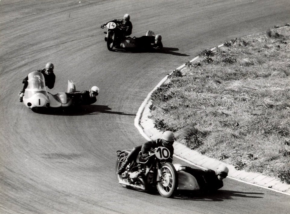 Motoren met zijspan nemen een bocht op het circuit. Aangekocht in 1977 van fotograaf C. de Boer. Identificatienummer 54-004451, NL-HlmNHA 54004451