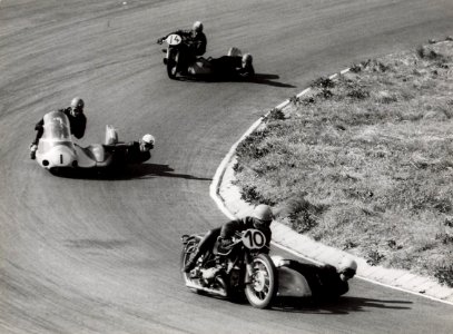 Motoren met zijspan nemen een bocht op het circuit. Aangekocht in 1977 van fotograaf C. de Boer. Identificatienummer 54-004451, NL-HlmNHA 54004451